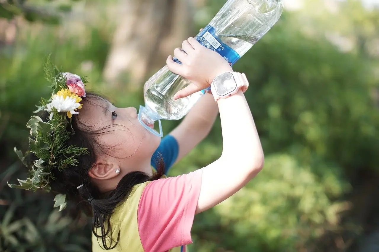 A little girl drinks from a bottle of water